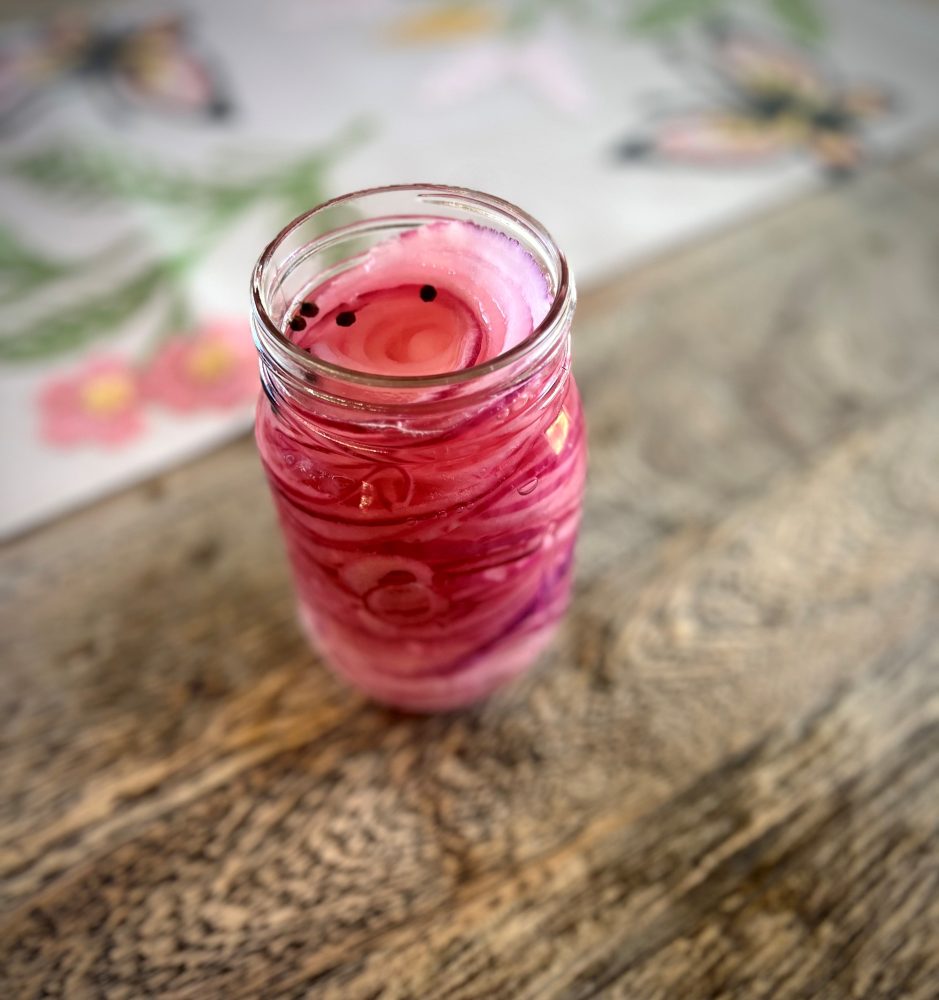 pickled onions in a jar with peppercorns